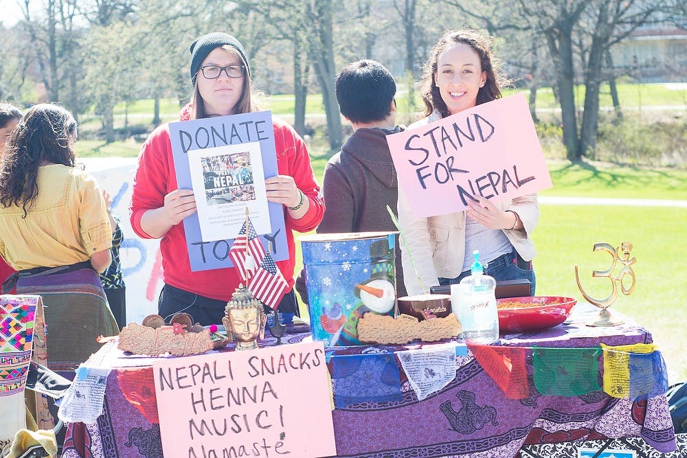 <p>Food science and Industrial business junior Andi Trubiano and human biology sophomore Danielle Ross hold signs in support of Nepal April 28, 2015, at The Rock on Farm Lane. The event is to help spread awareness and donations for Nepal. Hannah Levy/The State News</p>