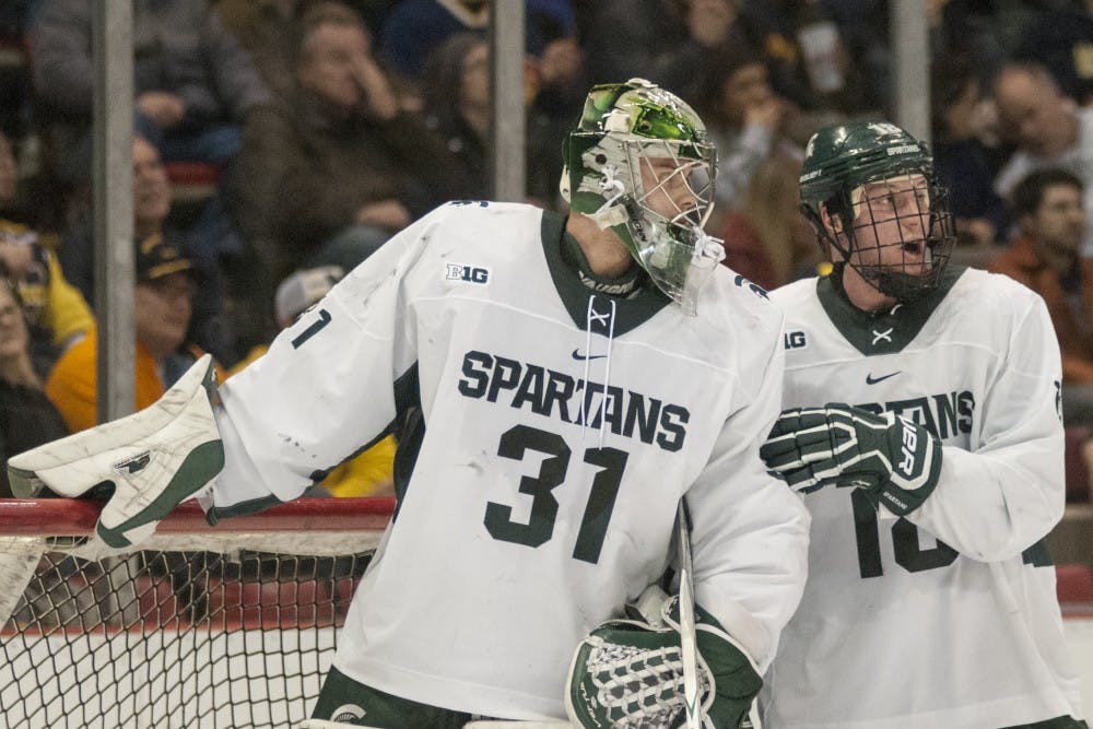 Junior defender Carson Gatt (18), right, consults freshman goaltender John Lethemon (31), left, during the third period of the men’s hockey game against the University of Michigan on Feb. 10, 2017 at Joe Louis Arena in Detroit. The Spartans were defeated by the Wolverines in an overtime shootout, 5-4. 