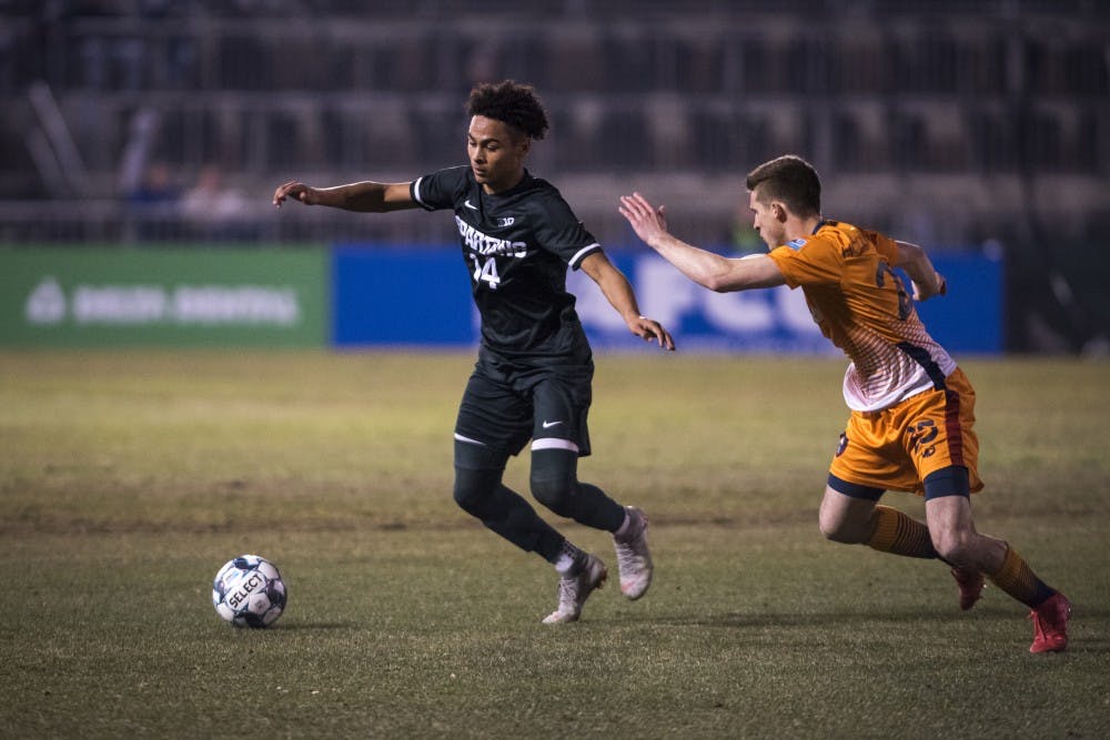 <p>Freshman defender Olu Ogunwale (14) handles the ball during the second half of the Capital Cup against Lansing Ignite FC at Cooley Law School Stadium in Lansing on Tuesday, April 16, 2019. Michigan State was defeated by Lansing Ignite, 4-0. </p>