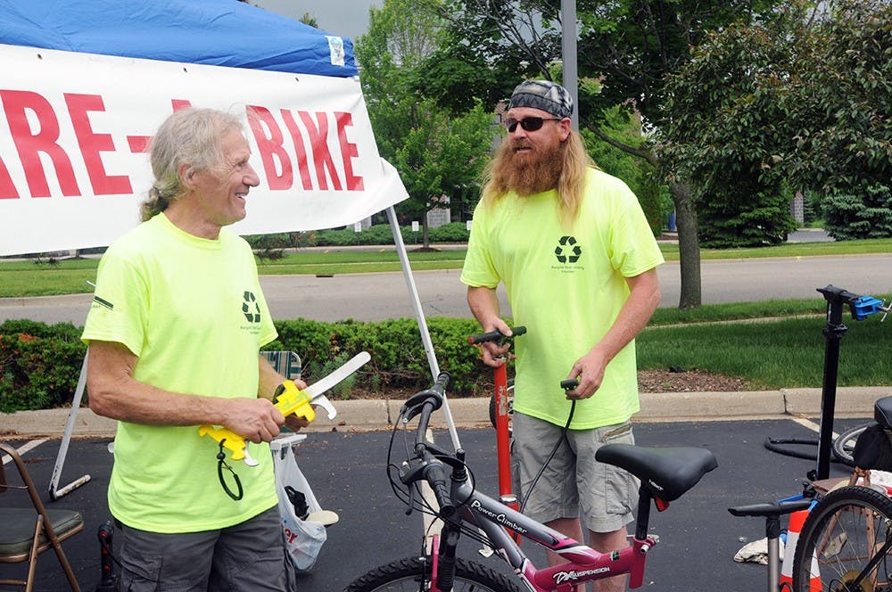 <p>Ron Zeeb (left) and Dave Meade stand at the Retire-A-Bike stand May 30, 2015 waiting for customers at the annual Recycle East Lansing event 1400 Abbott Road, in East Lansing. Asha Johnson/The State News. </p>