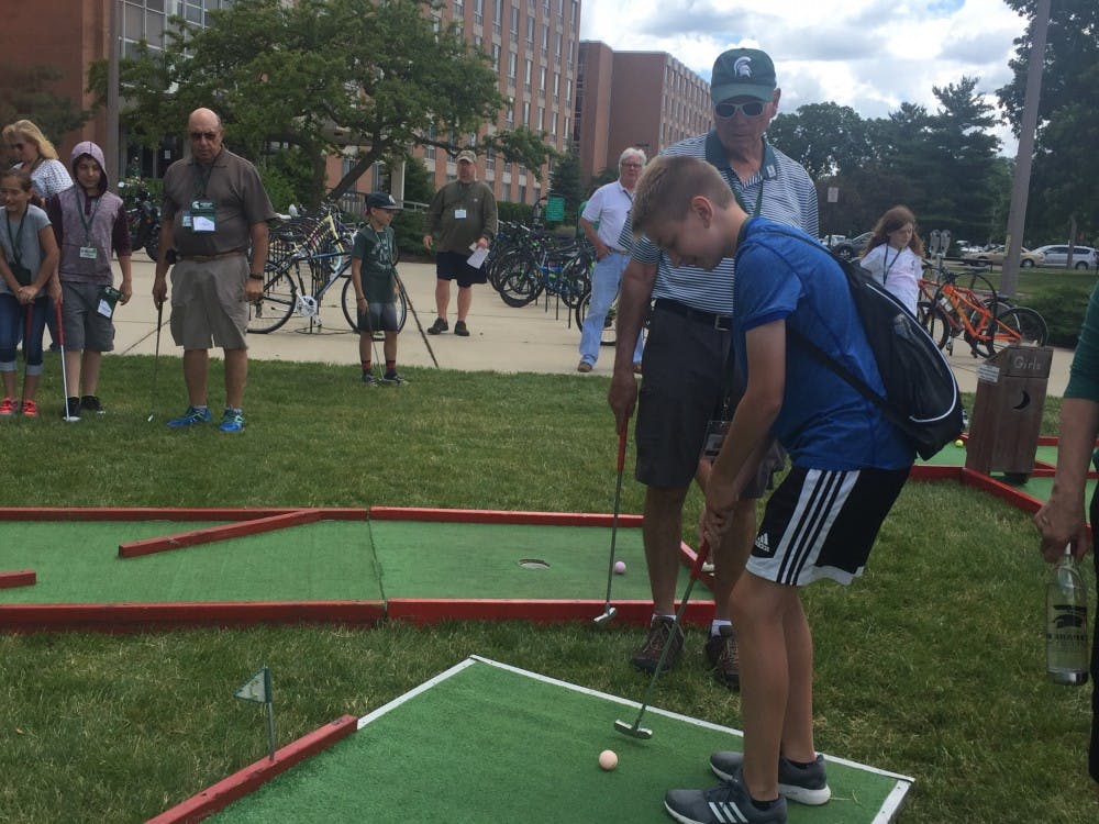 <p>MSU alumnus Dick Huntington and grandson Carter Parsons play minigolf outside of Holmes Hall June 27. Parsons traveled all the way from Ogden, Utah to spend time together with Huntington as attendees of the annual Grandparents University hosted by the MSU Alumni Association.</p>
