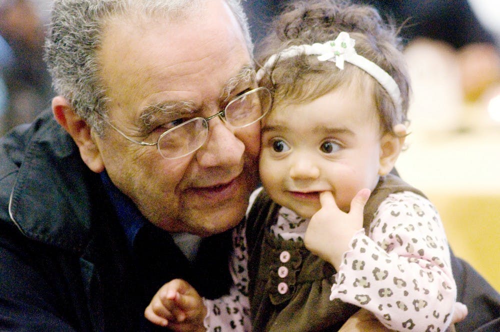 Okemos resident Dr. Aly Fadly, also the father-in-law of keynote speaker Dr. Mohammad Khalil, holds his granddaughter Aya Khalil, 9 months, Saturday at the Sixth Annual Diversity Dinner held at East Lansing High School, 509 Burcham Drive, East Lansing. The night consisted of speakers, prayer time, dinner and skits done by members of the community. McNeal/The State News