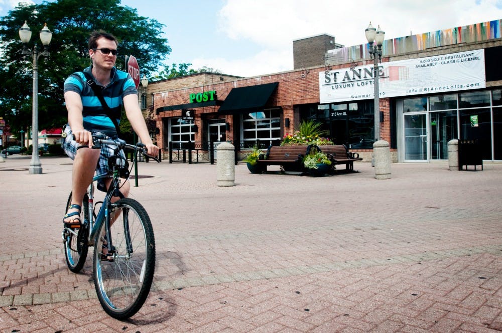 	<p>Studio art sophomore Volodimir Shcherbhl rides his bicycle past the future site of the St. Anne Luxury Lofts. The project, which consists of two separate buildings with both residential and retail space, is expected to break ground in September.</p>