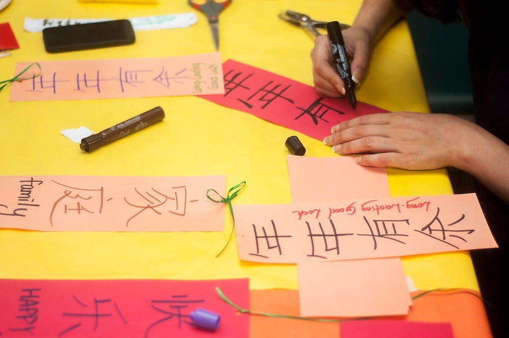 	<p>Biology senior Marina Louzada writes a phrase in Chinese calligraphy during the Lunar New Year celebration Jan. 26, 2014, at McDonel Hall Cafeteria. Participants had the opportunity to make paper lanterns, taste Chinese food, and view several performances. Danyelle Morrow/The State News</p>