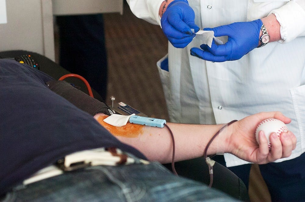 	<p>Microbiology senior Nicholas Roof holds a stress ball after Lansing resident Rebecca Durham finishes inserting a needle during a blood drive Feb. 5, 2014, at Holmes Hall. The American Red Cross held the blood drive as part of the Blood Battle against Michigan. Sierra Lay/The State News</p>