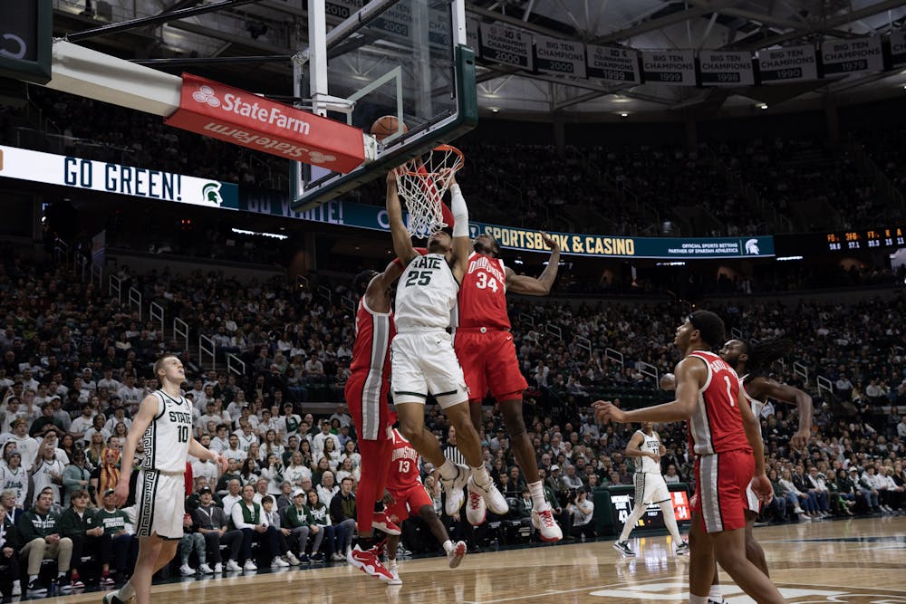 <p>Malik Hall hangs from the rim after his dunk attempt against Ohio State on March. 4, 2023</p>