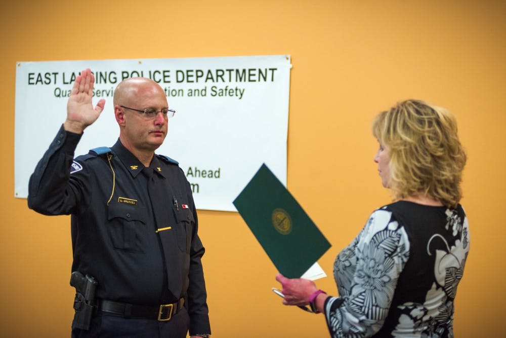 Interim Police Chief Larry Sparkes takes the oath of honor while being sworn in as East Lansing's chief of police on Aug. 25, 2017, at East Lansing Library. Sparkes has been appointed to the position in succession to Jeff Murphy. Murphy retired to take a position as the Director of Security for MSU’s College of Human Medicine research facility.