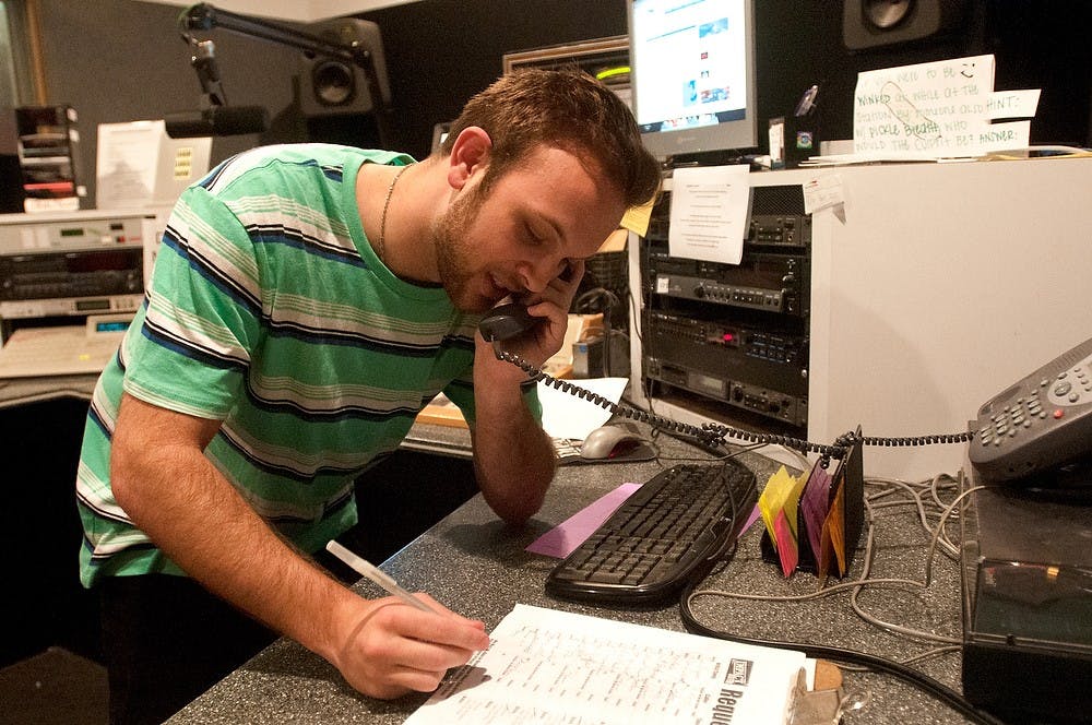 	<p>Communication senior Zac Segula answers a phone call from a listener on June 26, 2013, at The Impact radio station. The Impact still does not know if it will receive funding for the 2013-14 school year. Weston Brooks/The State News</p>