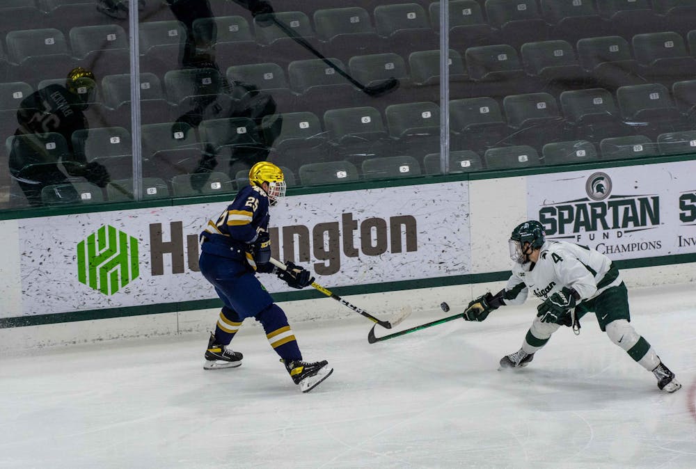 Freshman Nash Nienhuis (4) attempts to deflect a Notre Dame player's stick away from the puck in the third period but is unsuccessful. The Fighting Irish shutout the Spartans 2-0 on Feb. 27, 2021.