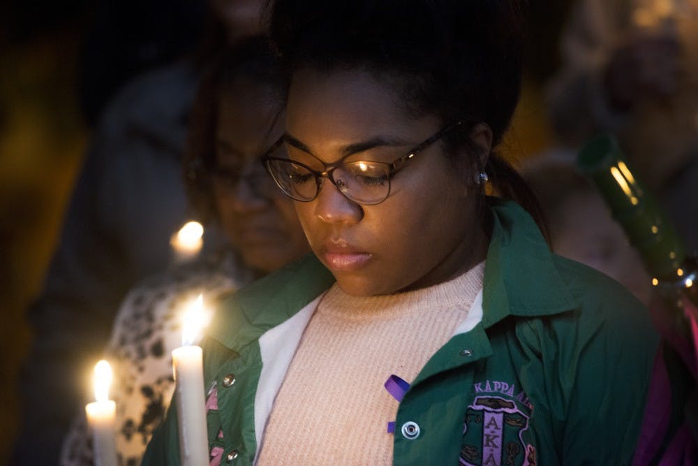 A woman bows her head in a moment of silence during a vigil on Oct. 21, 2016 at the Broad Art Museum. The purpose of the candlelight vigil was to honor survivors and individuals who have lost their life due to domestic violence. 