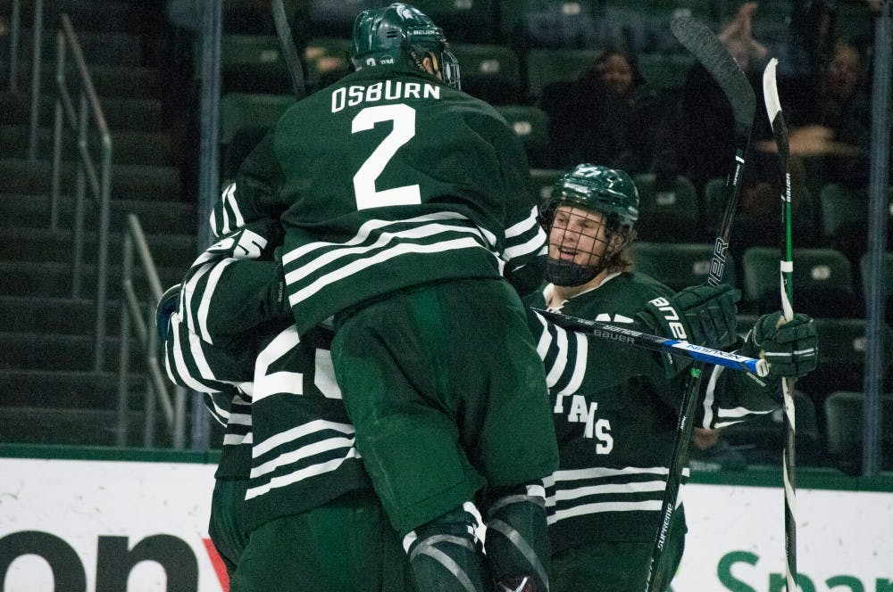 Sophomore defenseman Zach Osburn (2) jumps onto his teammates while celebrating a Spartan goal during the game against Ferris State on Nov. 11, 2016 at Munn Ice Arena. The spartans were defeated by the bulldogs, x-x. 