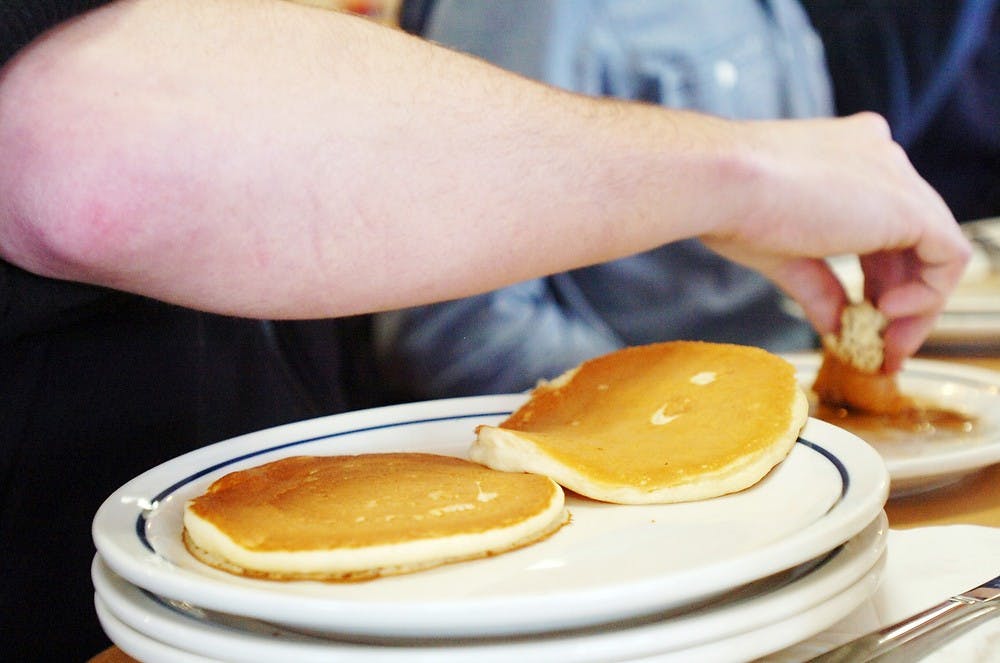 <p>Nursing junior Zachary Munger dips a pancake into syrup during a pancake eating contest March 24, 2014, at IHOP, 2771 E. Grand River Ave. The contest was hosted by Sigma Pi and MSU Up 'til Dawn and the proceeds went to St. Jude Children's Research Hospital. Emily Jenks/The State News</p>