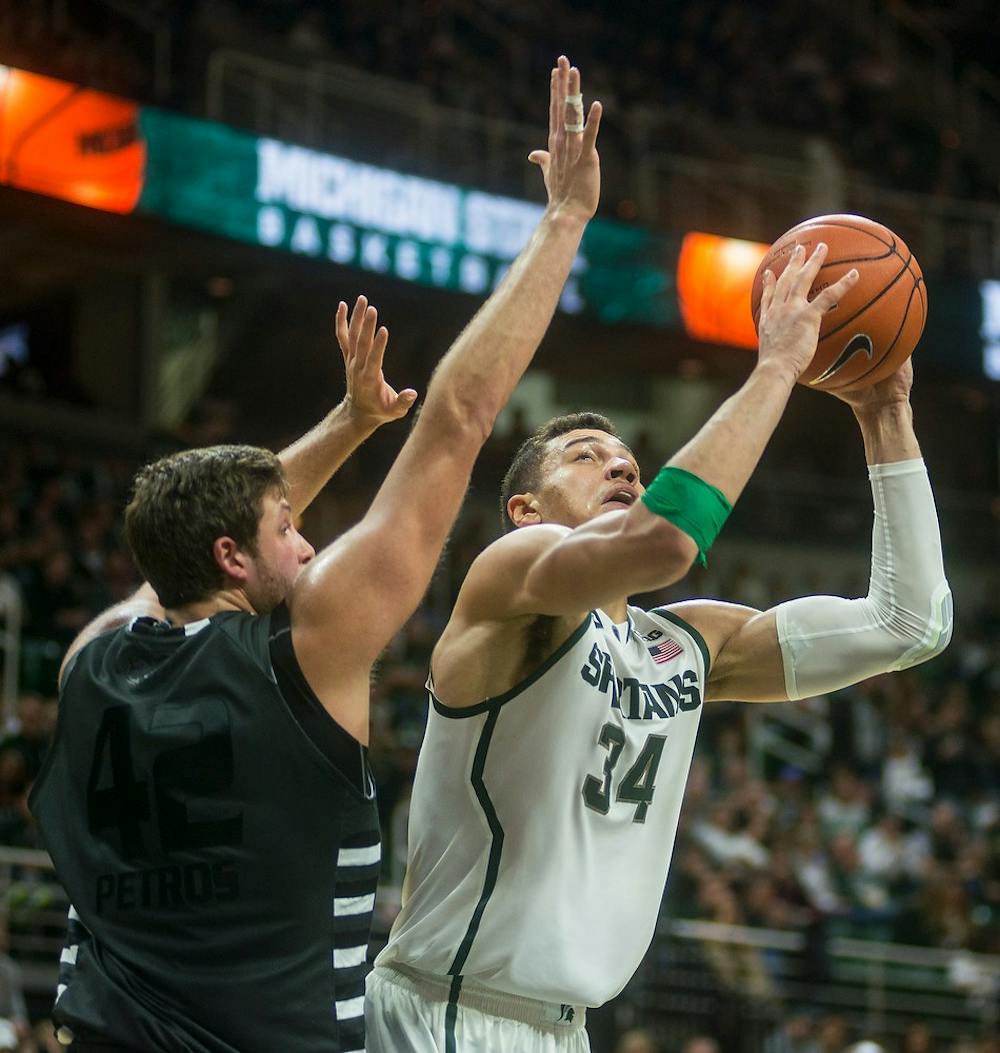 <p>Sophomore forward Gavin Schilling attempts a point over Oakland center/forward Corey Petros Dec. 14, 2014, during the game at Breslin Center. The Spartans defeated the Golden Grizzlies, . Erin Hampton/The State News</p>