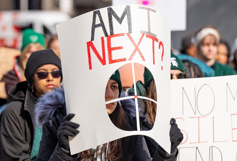 A MSU student holds a sign at the Michigan State Capitol on Feb. 20, 2023, during a sit-down protest against gun violence held by Michigan State University students, one week after a mass shooting took place on their campus.