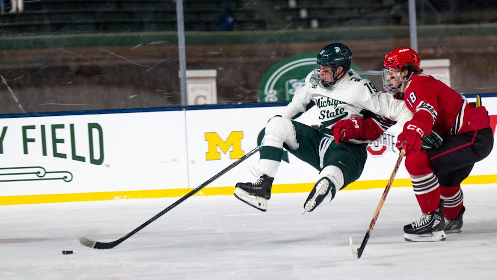Michigan State freshman forward Mikey DeAngelo (19) tries to move past Wisconsin graduate forward Owen Lindmark (18) at Wrigley Field in Chicago on Jan. 4, 2025. The Spartans' junior forward Daniel Russell (20) netted the overtime winner with under two seconds remaining, earning the weekend sweep over the Badgers.