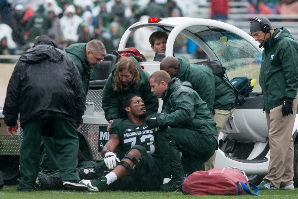 <p>Head coach Mark Dantonio looks down at sophomore offensive lineman Dennis Finley after Finley broke his right tibia and fibia in the second quarter of the Homecoming game against Purdue on Oct. 3, 2015, at Spartan Stadium. The Spartans defeated the Boilermakers, 24-21.</p>