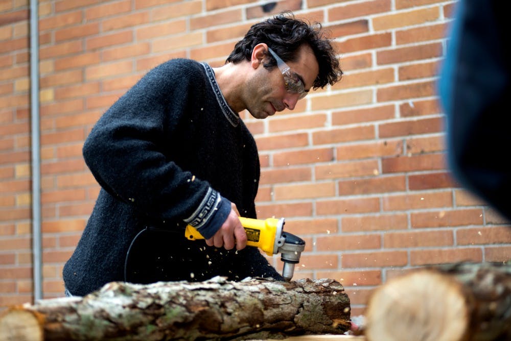 Plant, soil, and microbial sciences professor Greg Bonito drills holes in a log on April 22, 2016 at Bailey Hall. 