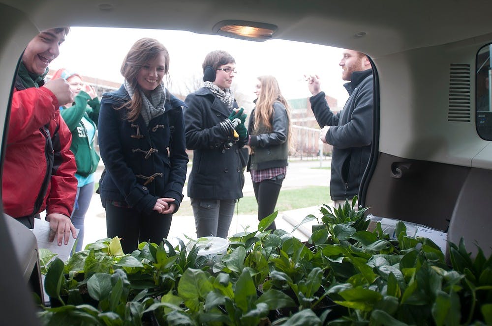 <p>Sustainable Spartans members and students look onto plants in the back of a vehicle April 22, 2015, at the Rock on Farm Lane during the Sustainable Spartans' Earth Day Extravaganza. The group handed out free plants and offered free bike repairs in celebration of Earth Day. Kelsey Feldpausch/The State News</p>