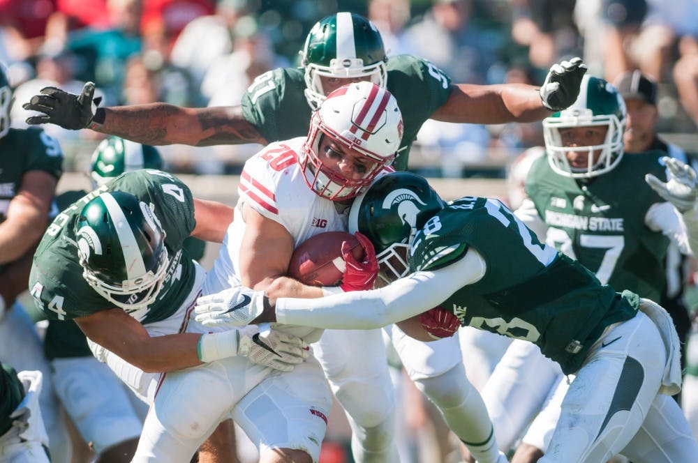 Wisconsin fullback Austin Ramesh (20) is tackled by sophomore safety Grayson Miller (44), defensive end Robert Bowers (91) and freshman safety David Dowell (28) during the game against Wisconsin on Sept. 24, 2016 at Spartan Stadium. The Spartans were defeated by the Badgers, 30-6.