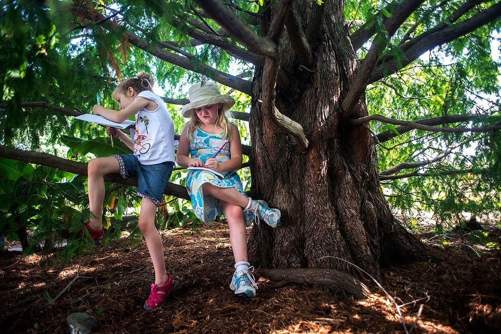 	<p>From left, Okemos resident Meghan Szidik, 7, and Farmington Hills, Mich., resident Miranda Ledebnick, 7, sit on a tree while they write July 9, 2013, at the Michigan 4-H Children&#8217;s Garden during the Garden Writers Workshop. The three-day workshop will give children the chance to write in the garden outdoors. Justin Wan/The State News</p>