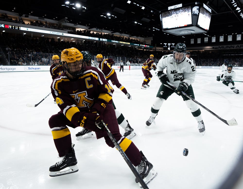 Senior forward Erik Middendorf (24) tries to steal the puck from a University of Minnesota player at Munn Ice Arena on Dec. 2, 2022. The Spartans lost to the Gophers with score 5-0. 