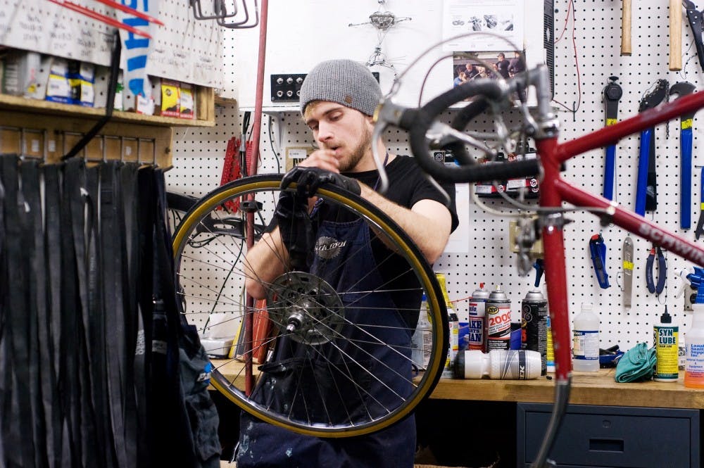 Jared Dorvinen, an English and Spanish senior, works on a tire before attaching it to a bike. MSU Bikes Services Center offers workshops during winter months to help students learn how to fix bikes on their own. Alethia Kasben/The State News