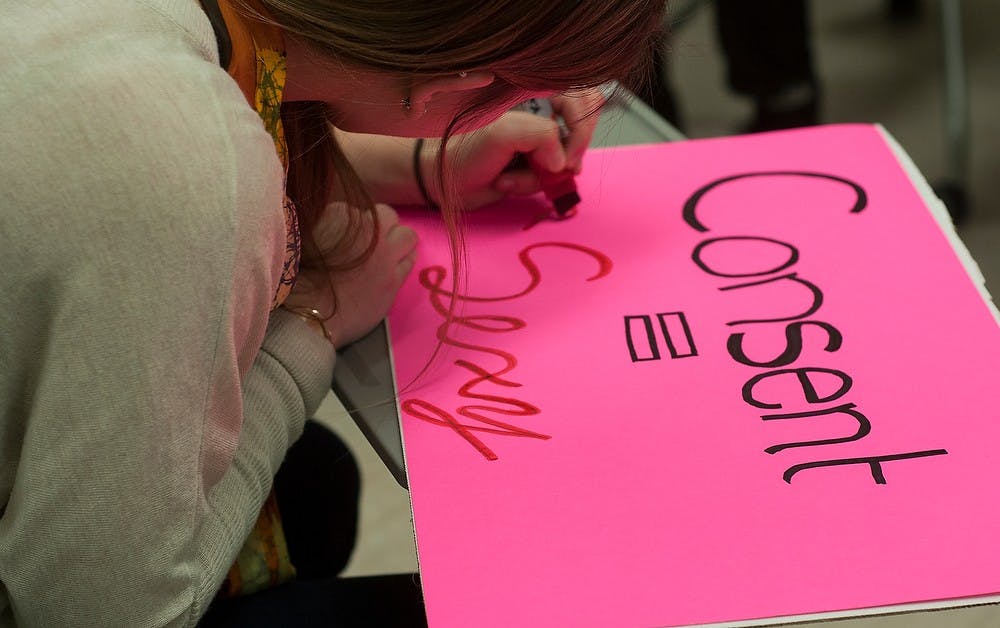 <p>Public policy junior Emma Walter writes, "Consent = Sexy" on Feb. 10, 2015, at Wells Hall. Posters were made during an MSU Students for Choice meeting prior to a protest against sexual violence on Valentine's Day.  Alice Kole/The State News</p>