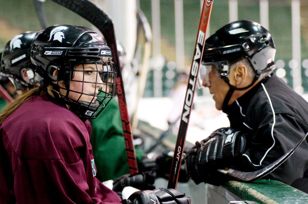 Sophomore forward Alex Kann looks onto the ice as assistant coach Chris Baryames Jr. talks to other players of the women's ice hockey team during their practice Monday night at Munn Arena. To support their club team expenses, they are having a fundraiser tonight from 6-9 p.m. at BD's Mongolian Grill, 2080 W. Grand River Ave. in Okemos. Derek Berggren/The State News