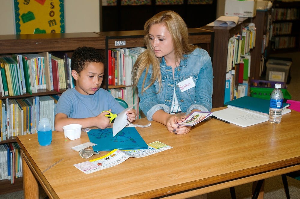 <p>Lansing resident Dallas Lott, 7, left, follows instructions from marketing freshman Heather Rauch on Sept. 29, 2014, at Riddle Elementary School, 221 Huron Street. Lott and Rauch participated in the Capital Area Literacy Coalition which provides one on one help to children, teens, and adults who are struggling with writing and reading. Jessalyn Tamez/The State News</p>