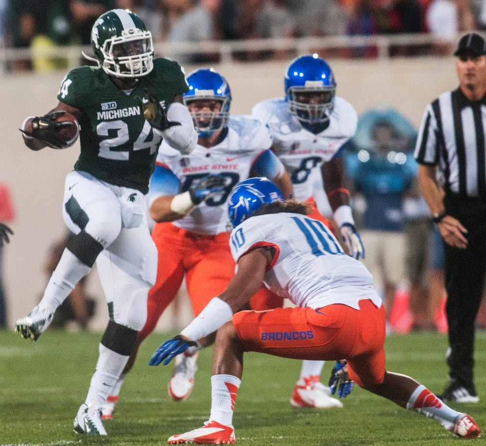 Junior running back Le'Veon Bell hurdles sophomore Boise State safety Jeremy Loane Friday night Aug. 31, 2012 at Spartan Stadium. Bell ran for a career high 210 yards in a 17-13 win against Boise State in the Spartans home opener. Adam Toolin/The State News