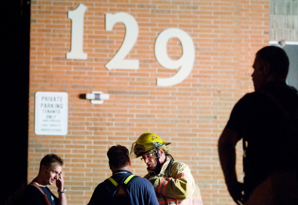 	<p>East Lansing firefighter Jim Hudson, center, talks to fellow firefighter Jeff Lund, left center, as first responders clean up and investigate a fire that erupted Aug. 15 at 129 Burcham Apartments. The fire began in an apartment on the second floor and spread up the back wall. Kat Petersen/The State News</p>