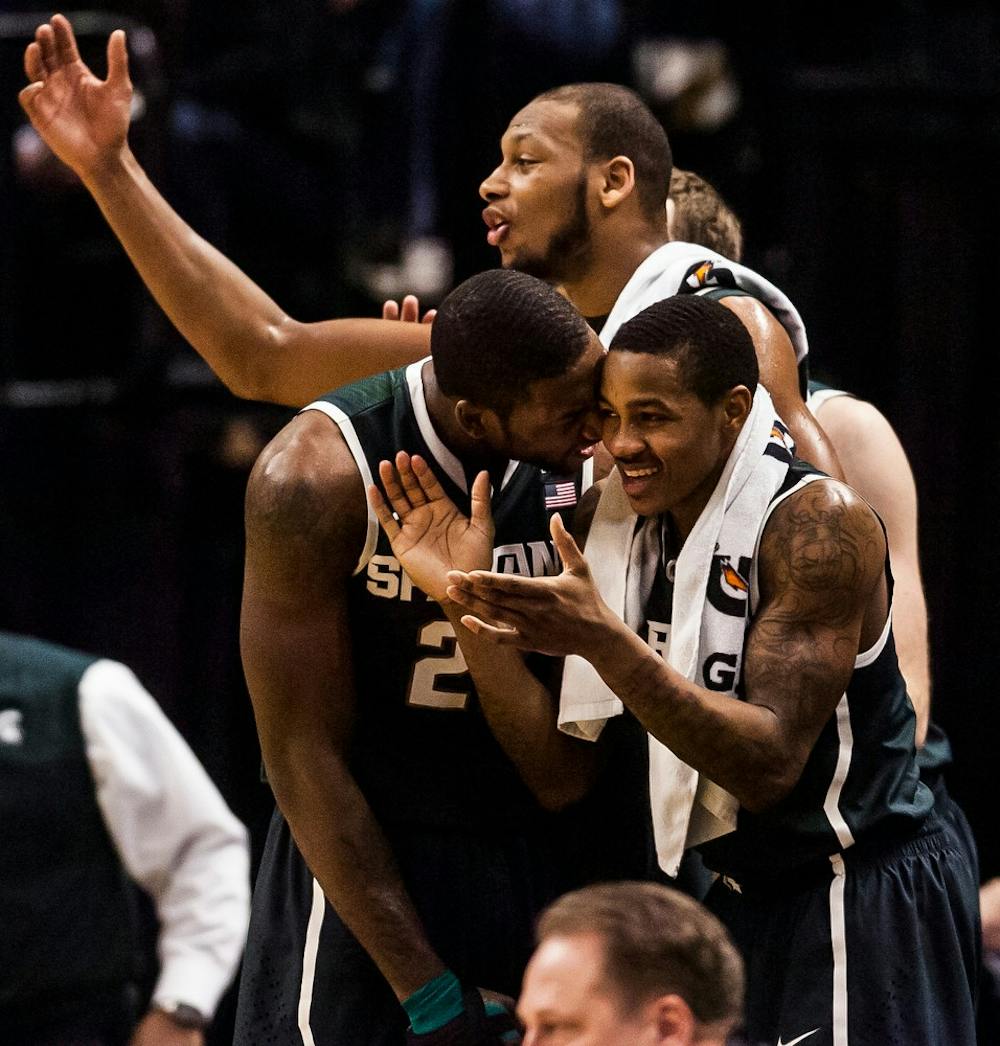 <p>Junior forward Branden Dawson, left, celebrates with senior guard Keith Appling as senior forward Adreian Payne waves his hands to hype up the crowd March 15, 2014, during a game against Wisconsin at the Big 10 tournament in Indianapolis. The Spartans won, 83-75. Erin Hampton/The State News</p>