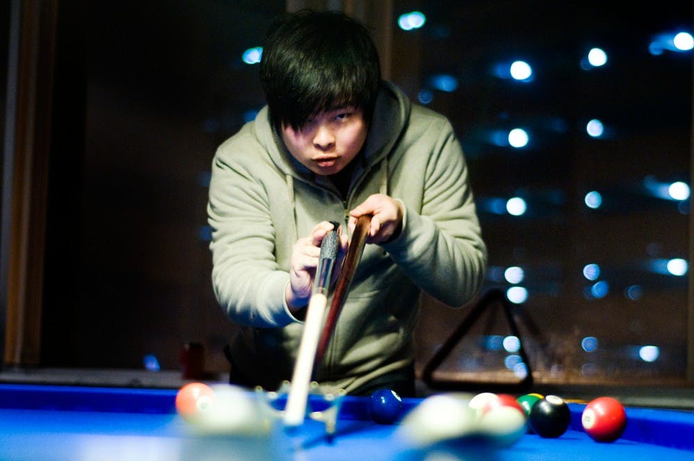 Supply chain management freshman Boren Lu finishes one of his shots at the pool table Saturday evening, Feb. 3, 2012, at Heart Beats. Heart Beats is a karaoke and billiards lounge which caters towards the growing population of international students at MSU located at 301 M.A.C. Avenue. Anthony Thibodeau/The State News