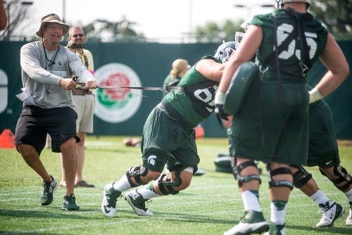 Offensive line coach Mark Staten runs practice drills Aug. 2, 2014, at the practice field outside Duffy Daugherty Football Building. Danyelle Morrow/The State News