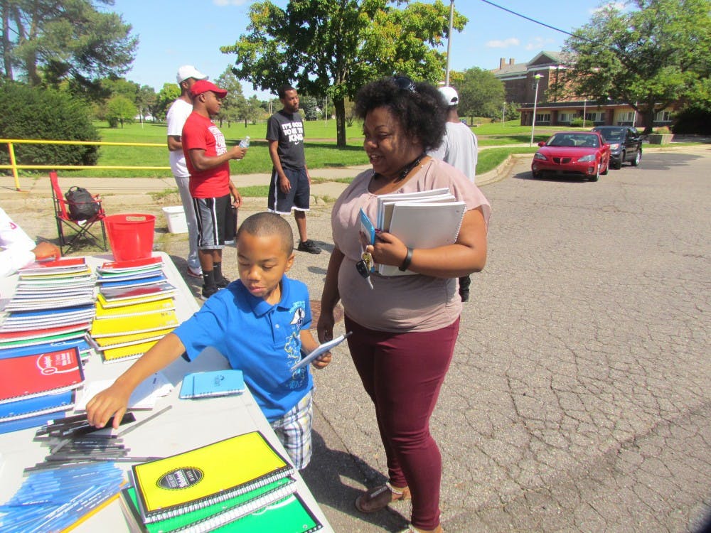 Michelle Coleman, right, and her son Malik Nichols, 7, look at school supplies on Sept. 3, 2016 at 730 W Maple St. in Lansing. 