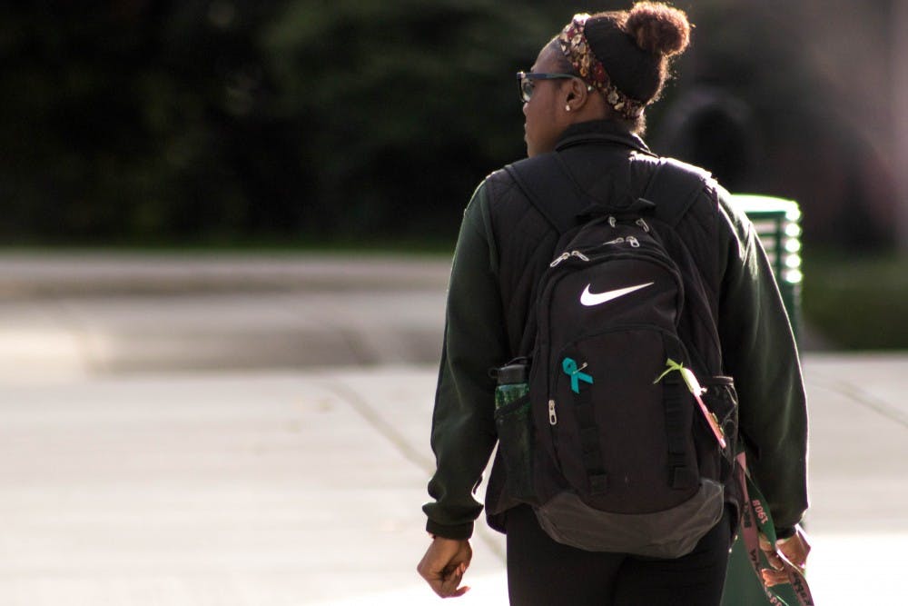 A student crosses Harrison in front of Brody Hall on Sept. 26, 2018. The teal ribbon symbolizes support for sexual assault survivors.