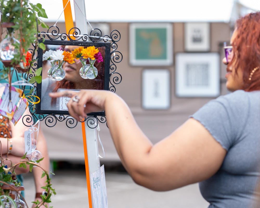 Visitors looking at art and other items on sale for the East Lansing Art Festival at Michigan State University on May 18, 2024.