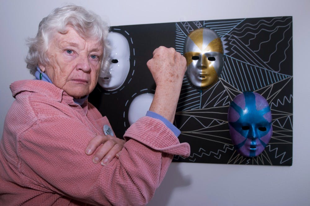 <p>WRA professor and feminist activist Penny Gardner poses for a portrait on Nov. 19, 2015 in Bessey Hall. Gardner found a way of incorporating feminism and hip-hop into her WRA class. The artwork shown behind her is from a project completed by students demonstrating the variety of masks females wear.  </p>