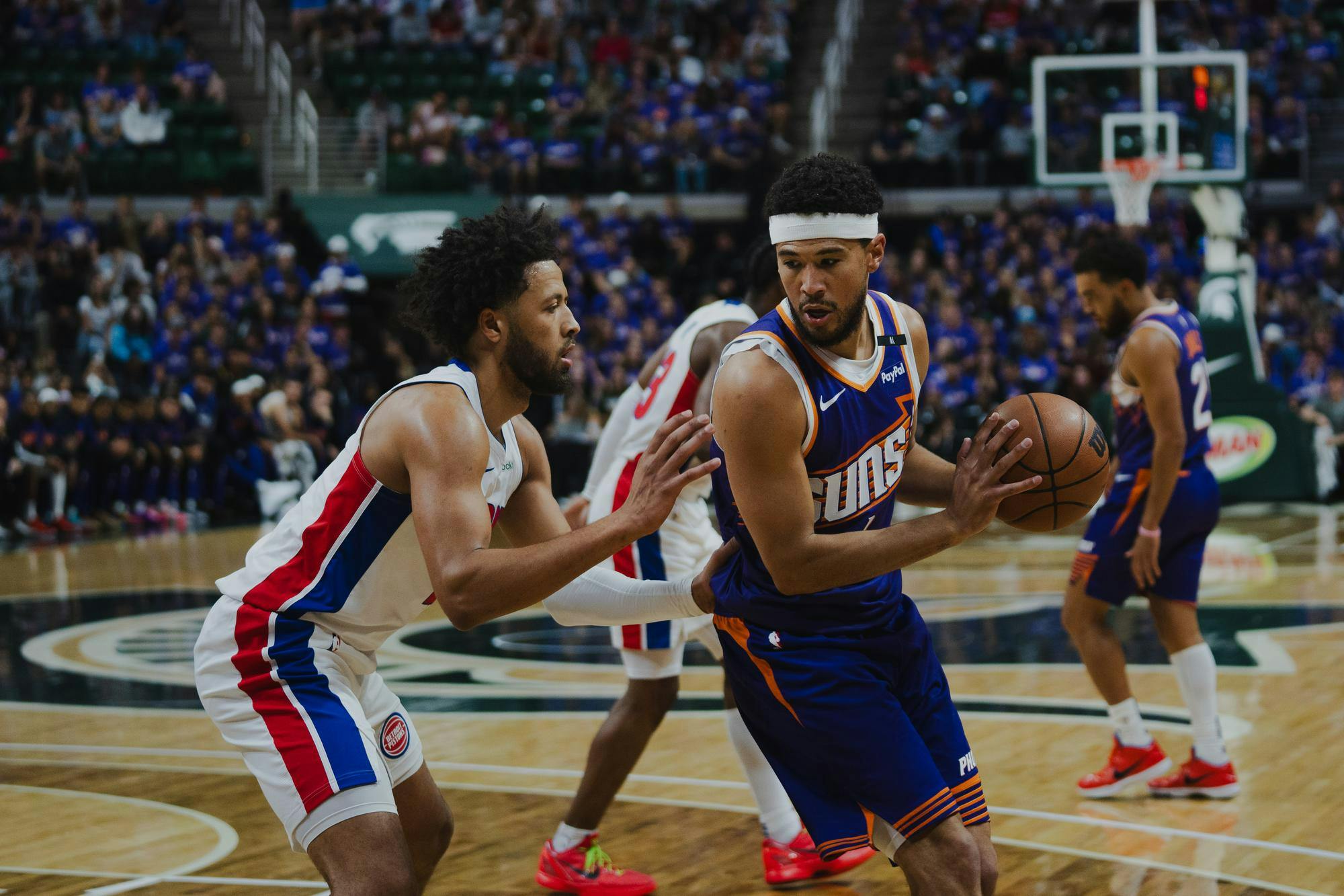 <p>Phoenix Suns guard Devin Booker (1) posts up Detroit Pistons point guard Cade Cunningham (2) during a preseason NBA game at the Breslin Center on Oct. 8, 2024.</p>