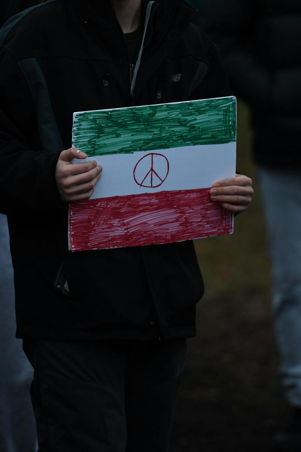 A sign is held by a protester during a protest against war in Iran at The Rock on campus on January 10, 2020. 