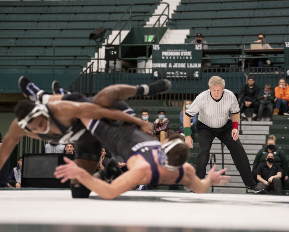 The referee watches the Foley-Cannon match in MSU’s meet against Northwestern at Jenison Field House on Friday, Feb. 11, 2021. 