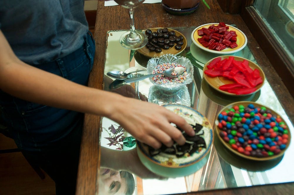 	<p>Residential College of Arts and Humanities senior Abbie Heath adds toppings to vegan chocolate mouse, Sept. 14, 2013, at Sprout and the Bean, 127 Allen St., in Lansing. Heath and her friends met for dinner at the in-home restaurant, which opened its doors for the first time in a year. Danyelle Morrow/The State News</p>