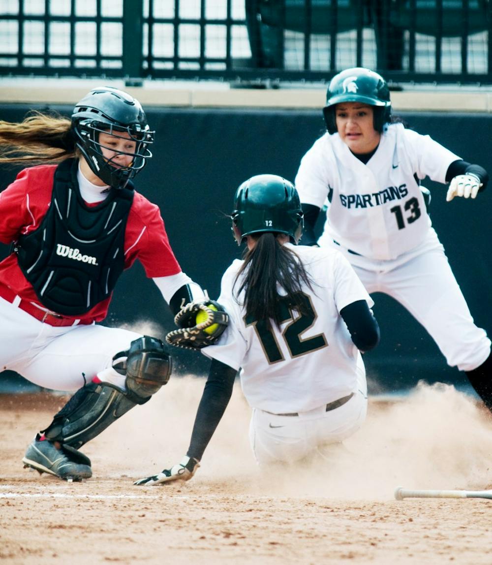 Senior shortstop Lindsey Hansen slides into home plate as Wisconsin catcher Maggie Strange attempts to get her out during Saturday's game at Secchia Stadium. Hansen was ruled safe and scored two runs to help the Spartans defeat the Badgers, 8-0. Lauren Wood/The State News
