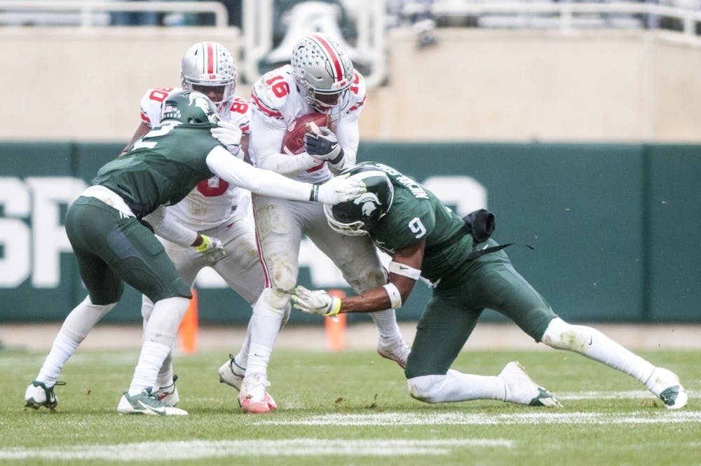 Junior safety Montae Nicholson (9) and senior cornerback Darian Hicks (2) tackle Ohio State quarterback J.T. Barrett (16) during the game against Ohio State on Nov. 19, 2016 at Spartan Stadium. The Spartans were defeated by the Buckeyes, 17-16.