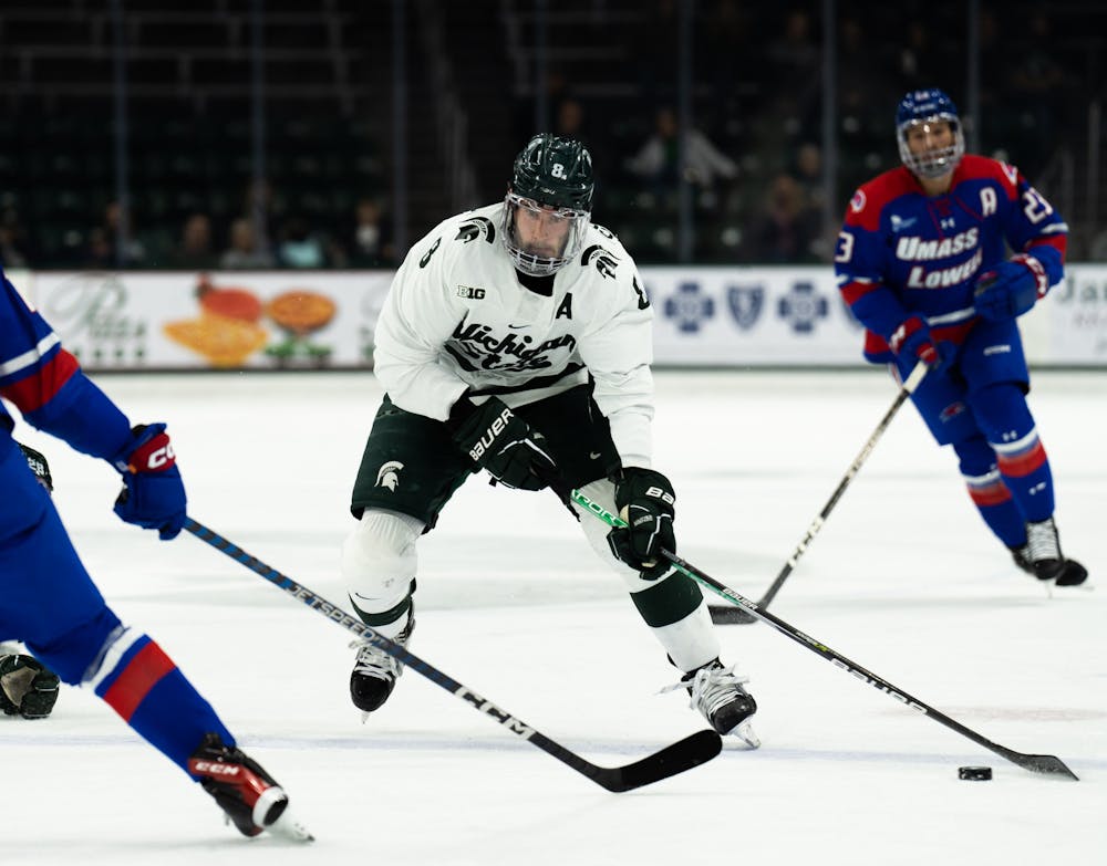 <p>5th-year defenseman Cole Krygier (8) fights off UMass players during a game at Munn Ice Arena on Oct. 13, 2022. The Spartans defeated the Minutemen with a score of 4-3. </p>