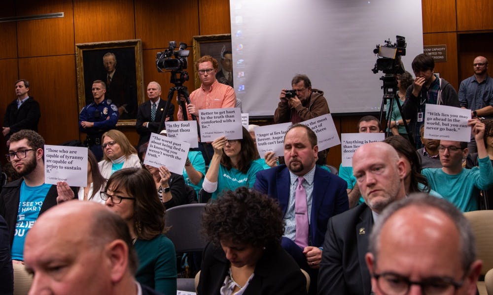 <p>Nassar survivors and their supporters and allies hold up signs during the Board of Trustees meeting Dec. 14, 2018 at the Hannah Administration Building.</p>