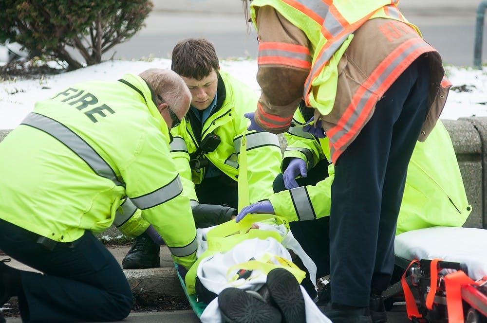 <p>Members of the East Lansing Fire Department assist a pedestrian that was struck by a moving vehicle while crossing the road April 15, 2014, on west-bound Grand River Ave. in front of The Peanut Barrel. Danyelle Morrow/The State News</p>