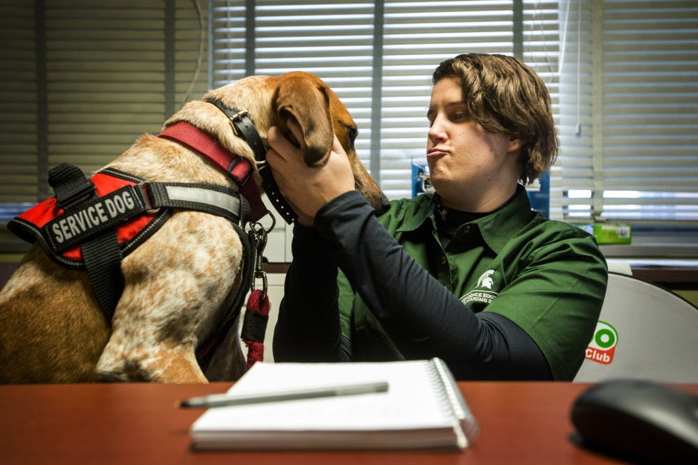 Graduate student Caitlin Thompson plays with her service dog, Charlie, on Jan. 19, 2017 at Akers Hall. Thompson works as a facilities supervisor in Akers Hall.  Charlie, like all service dogs, are considered a part of the owner and the owner and dog spend a majority of their working lives together. Charlie is a service dog for medical alert and response and he performs tasks such as blocking entry ways, creating space and alerts for medication.
