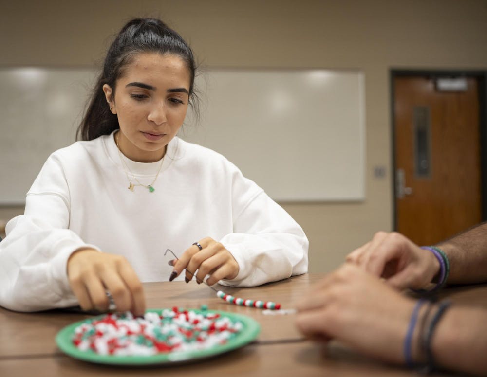 <p>Human resources and labor relations junior Marissa Habhab makes a bracelet using beads with the Lebanese flag colors at the Lebanese Student Association's Bracelets for Lebanon event on Oct. 2, 2024.</p>