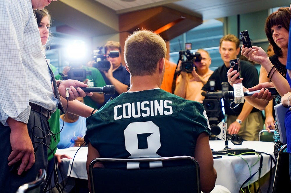 	<p>Fifth year senior quarterback Kirk Cousins is surrounded by microphones and bright lights as he addresses a battery of questions during Monday&#8217;s media day on the fourth floor of Spartan Stadium. </p>